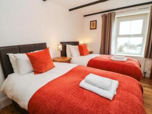 um quarto com 2 camas com lençóis vermelhos e brancos em Potters Cottage em Lynton