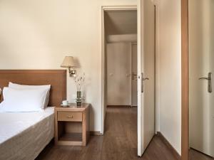 a bedroom with a bed and a table with a lamp at Strada Marina Hotel in Zakynthos