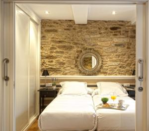 a bedroom with two beds and a stone wall at Catedral Site by Como en Casa in Santiago de Compostela