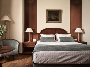 a bedroom with a large bed and a chair at Strada Marina Hotel in Zakynthos