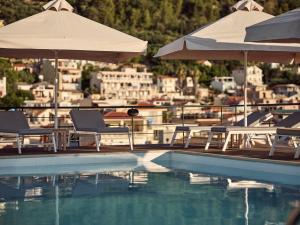 a swimming pool with chairs and umbrellas and a city at Strada Marina Hotel in Zakynthos