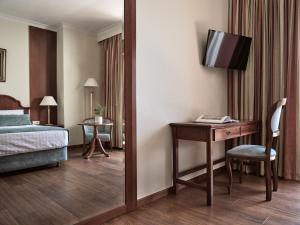 a hotel room with a bed and a desk with a television at Strada Marina Hotel in Zakynthos