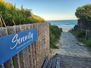 a sign on a fence next to a beach at Serenity Diamond Beach in Diamond Beach