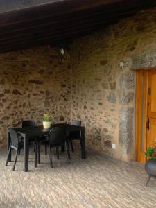 un tavolo nero e sedie in un muro di pietra di VUT Rural - Boente a Arzúa