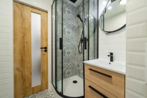 a bathroom with a shower and a sink and a mirror at Stylish retro apartment in Rakovník