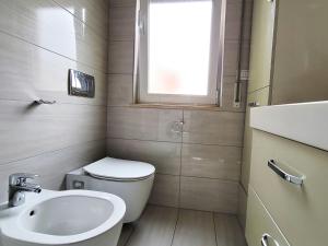 uma casa de banho com um WC, um lavatório e uma janela em Quiet Apartment near Tirana Lake em Tirana