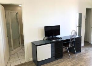 a room with a desk with a television and a chair at Motel Moreau in Saint-Félicien