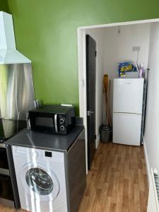 a kitchen with a microwave on top of a washing machine at Windsor stays 1 in Liverpool