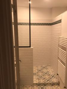 La salle de bains est pourvue d'une douche et de carrelage blanc. dans l'établissement Nid douillet bord de Loire, à Blois