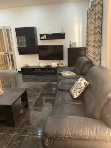 a living room with a leather couch and a television at sembene tourisme ngaparou in Ngaparou