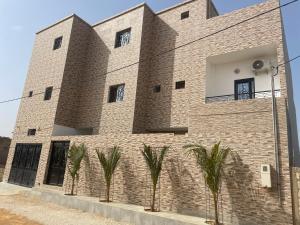 a brick building with palm trees in front of it at sembene tourisme ngaparou in Ngaparou