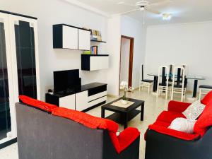 uma sala de estar com duas cadeiras vermelhas e uma televisão em SaVoa 869 em Gran Tarajal
