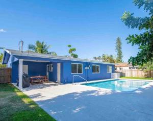 uma casa azul com uma piscina em frente em Cozy Blue house blocks from beach with Private Pool, BBQ, Backyard em Deerfield Beach