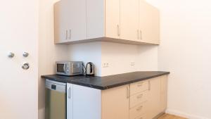 a small kitchen with white cabinets and a microwave at Pension Majesty in Berlin