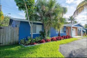 uma casa azul com palmeiras em frente em Cozy Blue house blocks from beach with Private Pool, BBQ, Backyard em Deerfield Beach