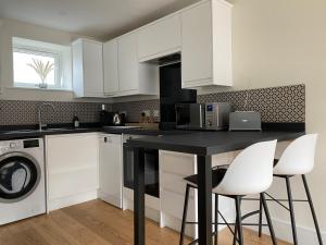 a kitchen with white cabinets and a black counter top at New studio apartment - minutes walk to Cathedral in Salisbury