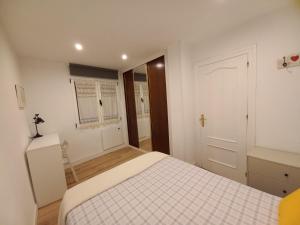 a white bedroom with a bed and a window at Rosario 14 Cimavilla in Gijón