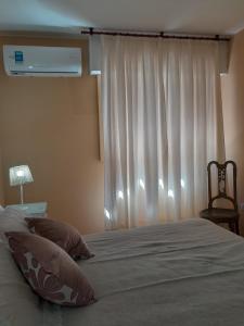 1 dormitorio con 1 cama con cortina blanca y ventana en Departamento en el centro de Mendoza en Mendoza