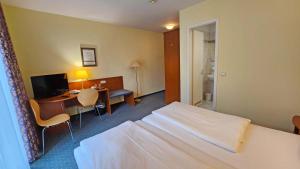 a hotel room with a bed and a desk with a computer at Hotel Amadeus Dresden Neustadt in Dresden