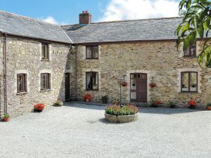 an old stone building with flowers in a courtyard at Anneth Lowen in Pentewan