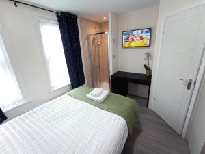 a bedroom with a bed and a window and a television at The Maple Studio - Self contained one bed studio flat in Oxford