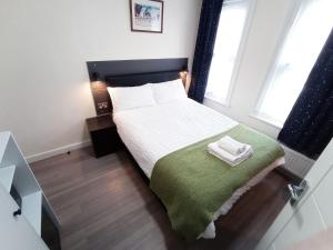 Dormitorio pequeño con cama con manta verde en The Maple Studio - Self contained one bed studio flat en Oxford