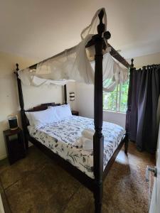 1 dormitorio con cama con dosel y ventana en Avalon Resort, en Kerikeri