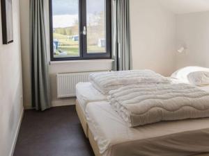 een slaapkamer met een bed en een raam bij Beautiful luxury holiday home with rural character in Ruinerwold
