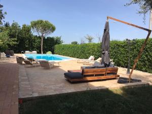 a patio with an umbrella and chairs and a pool at Belvilla by OYO Villa Due Pini Cavallino in Montecosaro