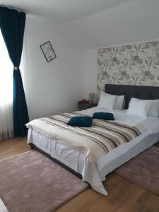a bedroom with a large white bed with blue pillows at Casuta din Gradina in Horezu