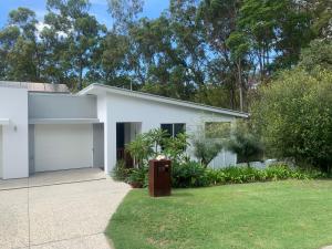 una casa blanca con garaje en Bush Beach Retreat en Caloundra