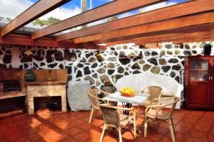 una sala da pranzo con tavolo, sedie e parete in pietra di Casa Rural Tio Pedro a Mazo