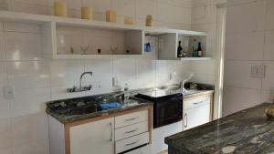 uma cozinha com um lavatório e um micro-ondas preto em Flat Independência em Porto Alegre