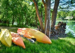dos kayaks y un montón de troncos junto a un árbol en Treetop River Cabins on the Guadalupe River, en Center Point