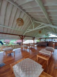 特特巴图Pondok Indah Bungalows Tetebatu的一个宽敞的凉亭，木地板上摆放着长椅和桌子。