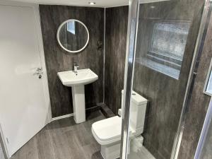 a bathroom with a sink and a toilet and a mirror at Airport Hideaway in Manchester