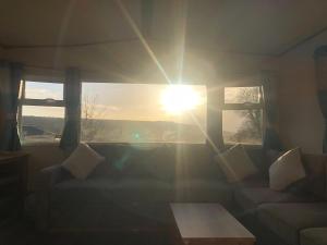 a living room with the sun shining through the windows at Classy caravan with ample space in Bembridge