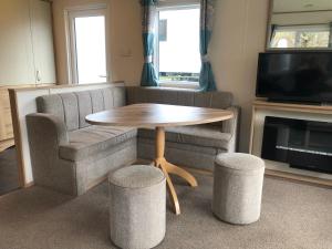 sala de estar con mesa, sofá y silla en Classy caravan with ample space, en Bembridge