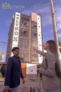 a man and woman standing in front of a building at MELTHON URBANS in Ayacucho