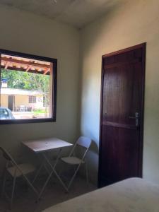 カシャンブにあるSítio Porta das Águasのテーブルと椅子2脚、ドアが備わる部屋