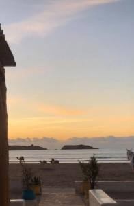 una puesta de sol en una playa con el océano en el fondo en Magnifique appartement avec terrasse prive vue mer en Esauira