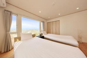 two beds in a room with a large window at Crystal Besso Shirahama in Shirahama