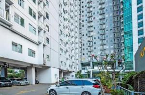 un coche aparcado en un estacionamiento frente a edificios altos en Easton Park Residence Jatinangor - GIANDARA, en Sayang