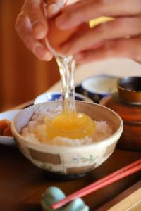 una persona vertiendo un huevo en un tazón de arroz en Kamenarien, en Ema
