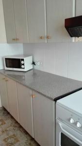 a kitchen with white cabinets and a counter with a microwave at Apartamento Guardamar 1D Estándar in Guardamar del Segura