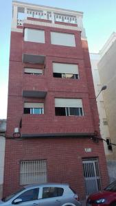 a red brick building with a car parked in front of it at Apartamento Guardamar 1D Estándar in Guardamar del Segura