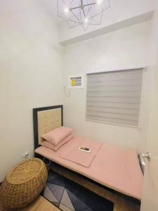 a small bedroom with a pink bed and a window at COZY PLACE TO RELAX VERDON PARC in Davao City