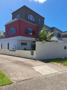 une maison rouge et blanche sur le côté d'une rue dans l'établissement Sunbrae Beach Sanctuary free high Fibre wifi, à Mount Maunganui