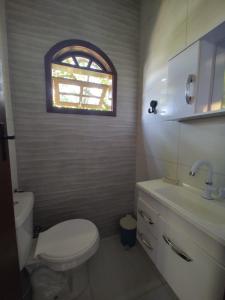 a bathroom with a toilet and a sink and a window at Hospedagem El Camino Del Viento in Teresópolis