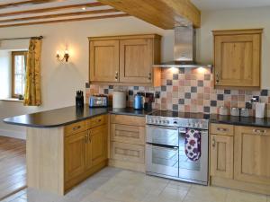 a kitchen with wooden cabinets and a stove top oven at The Mill - Om3 in Mydroilin